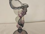 a glass vase on a stand on a white surface