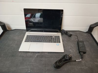 un ordinateur portable posé sur une table avec un chargeur