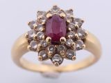a close up of a gold ring with a ruby stone surrounded by white diamonds