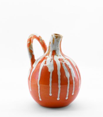 un petit vase orange orné d'une bande blanche