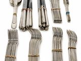 many forks and spoons laid out on a white surface