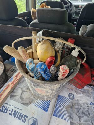 a bucket filled with assorted items on a table in the back of a car