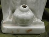 a white vase sitting on a stand on a green cloth