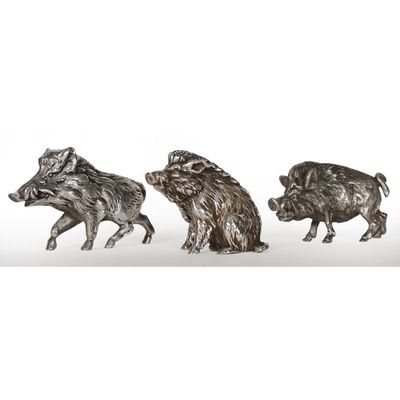 trois figurines en argent représentant des sangliers sur fond blanc