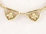 an image of a gold necklace with a flower design on it
