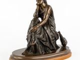 a bronze statue of a woman sitting on top of a wooden base