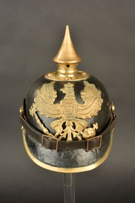 an old helmet with a gold decoration on it sitting on a stand