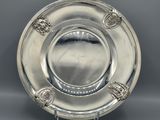 a silver plate on a stand on a gray background