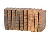 six vieux livres empilés sur une surface blanche