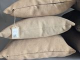 four pillows with tags on them sitting on a grey surface