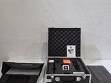 une mallette noire contenant un objet orange, posée sur une table blanche