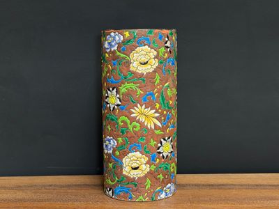 a brown vase with flowers on it sitting on a table