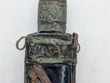an old bottle with a metal handle on a white wall