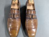 pair of brown leather shoes with buckles on them on a gray surface