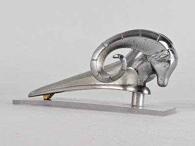 une sculpture métallique représentant une tête de bélier posée sur un socle