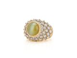 a close up of a ring with a green stone surrounded by diamonds