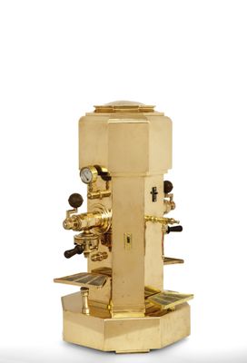 a gold coffee machine that is sitting on a white surface