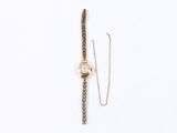 a close up of a watch and a chain on a white surface