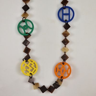 collier multicolore avec un monogramme sur une chaîne, sur fond blanc