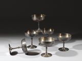 six verres à vin argentés et un verre à vin posés sur une surface blanche