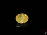 a yellow sapphire stone on a black surface