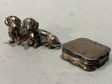 deux figurines de chiens en argent posées l'une à côté de l'autre sur une table