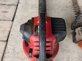a red and black blower and a chainsaw on the ground