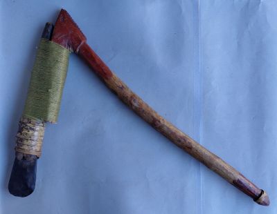 une très vieille hache posée sur une feuille de papier