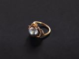 a gold and pearl ring on a black surface