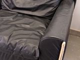 a black leather couch in a room with a white wall