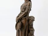 bronze statue of a woman holding a child on a wooden base