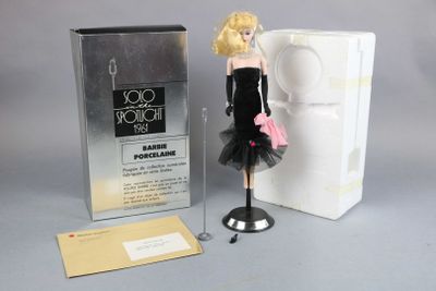 barbie doll in a black dress next to a box of perfume