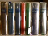 Plusieurs livres sont empilés sur une étagère devant une fenêtre