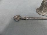 a silver spoon with a bell on it on a table