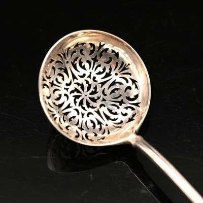 a silver spoon with a design on it on a black surface
