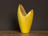 un vase jaune posé sur une table, sur fond noir