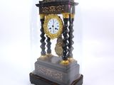 a small clock under a glass dome on a table