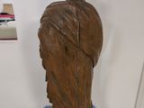 a wooden statue of a woman sitting on a blue pedestal