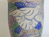 a vase with a bird on it on a white surface