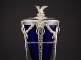 un vase en verre argenté et bleu surmonté d'un oiseau