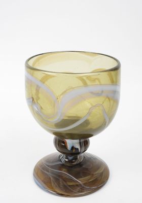 un bol en verre jaune posé sur un socle en bois, sur fond blanc