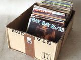 une boîte en carton remplie de disques de toutes sortes, posée par terre