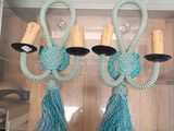 two teal colored wall sconces with tassels hanging from them