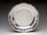 a silver plate on a white surface with a black background