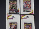 Trois paquets de cartes à collectionner Pokémon sont posés sur une table noire.
