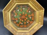 une assiette richement décorée, dorée et verte, ornée d'oiseaux et de fleurs
