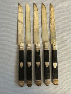 five knives with black handles on a white surface