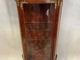 une vitrine ancienne en bois, dotée de portes vitrées et de garnitures dorées