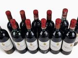 six bottles of red wine lined up in a row on a white surface