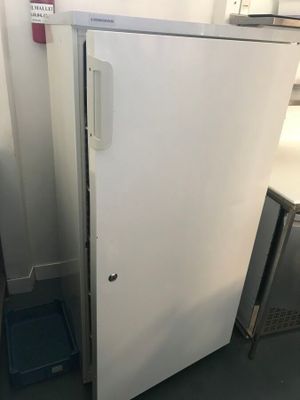 a white refrigerator sitting in a kitchen next to a blue trash can